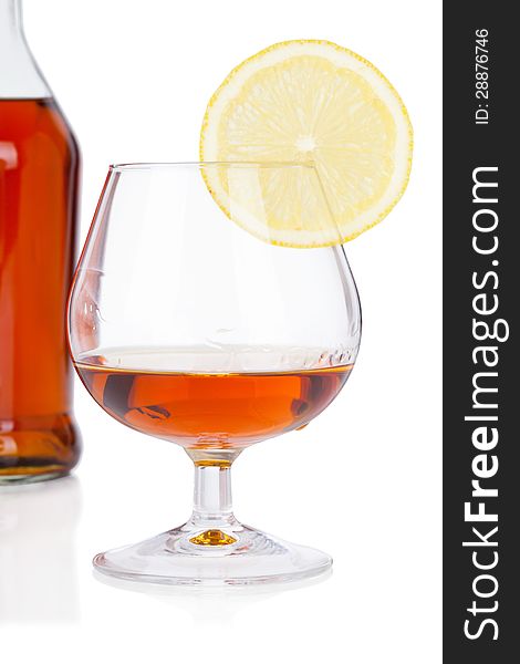 Glass of cognac with bottle on white background