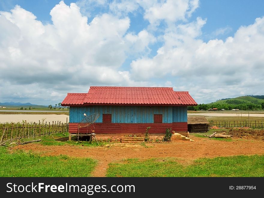 Tipical laotian country house made of wood painted in traditional colors in a rural landscape with a storm approaching