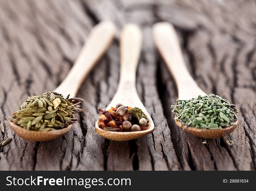 Variety of spices in the spoons on an old wooden table. Variety of spices in the spoons on an old wooden table.