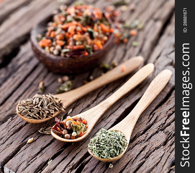 Variety of spices in the spoons on an old wooden table. Variety of spices in the spoons on an old wooden table.