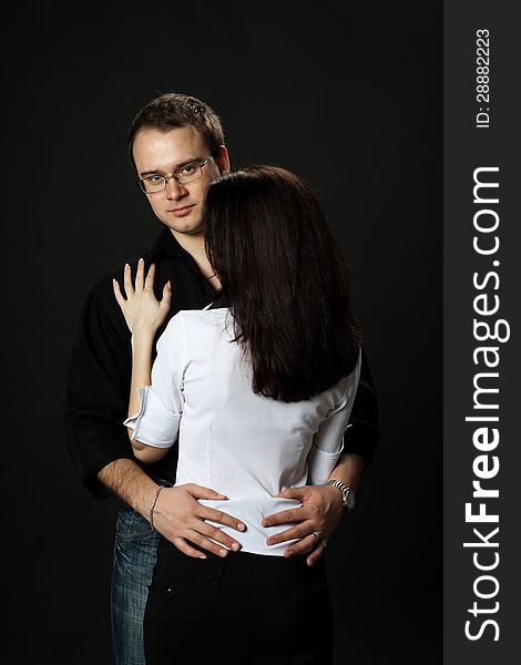 Young beautiful couple posing standing in studio on black background. Young beautiful couple posing standing in studio on black background
