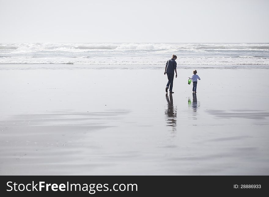 Mother and daughter walk on the beach out towards the Pacific Ocean. Mother and daughter walk on the beach out towards the Pacific Ocean.