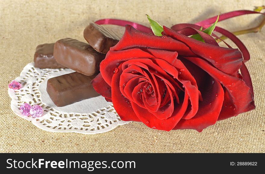 Single red rose with chocolate candies on the napkin. Single red rose with chocolate candies on the napkin