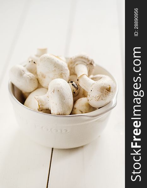 Common mushrooms in a white ceramic bowl