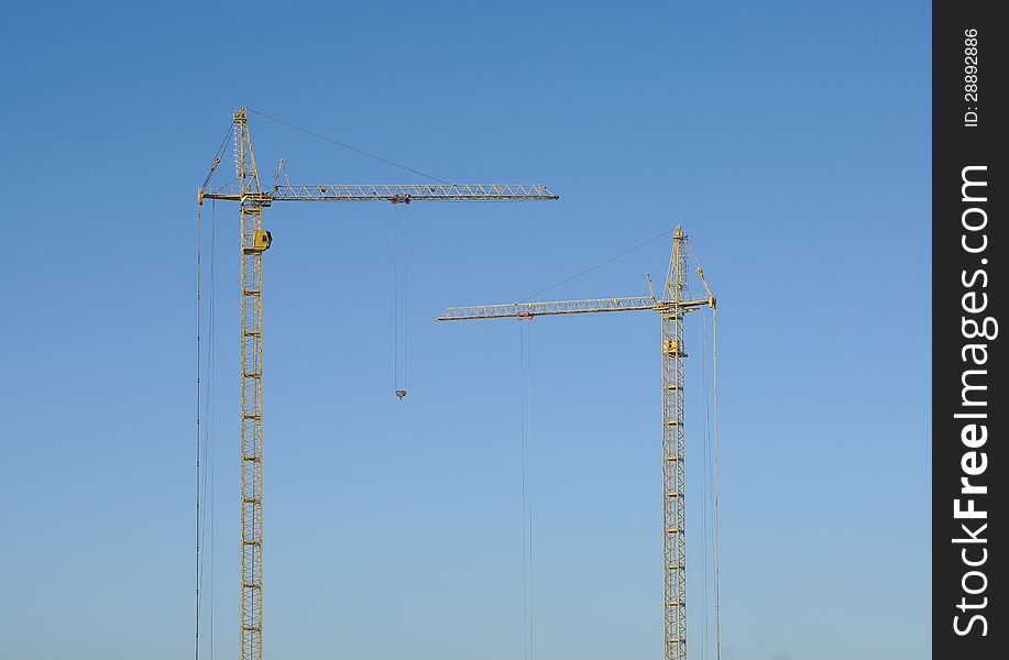 Silhouette of two cranes against the blue sky