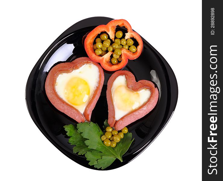 Sausages in the form of two hearts and fried eggs on a black plate isolated on white. Sausages in the form of two hearts and fried eggs on a black plate isolated on white