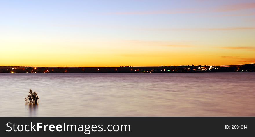 Dusk over water looking onto houses in the distance. Dusk over water looking onto houses in the distance