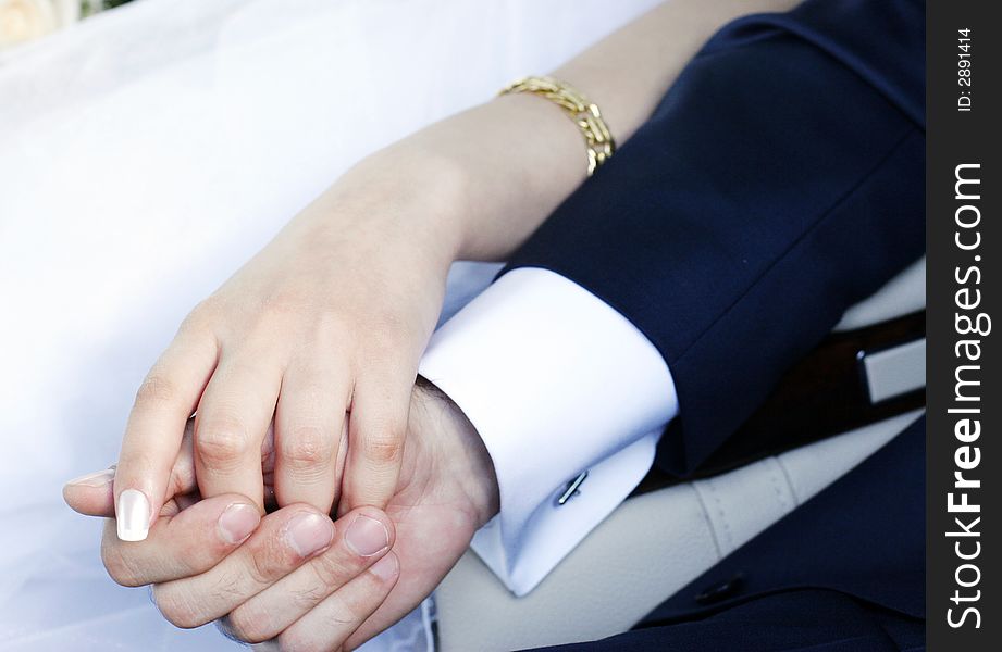 Bride and groom hands over wedding dress