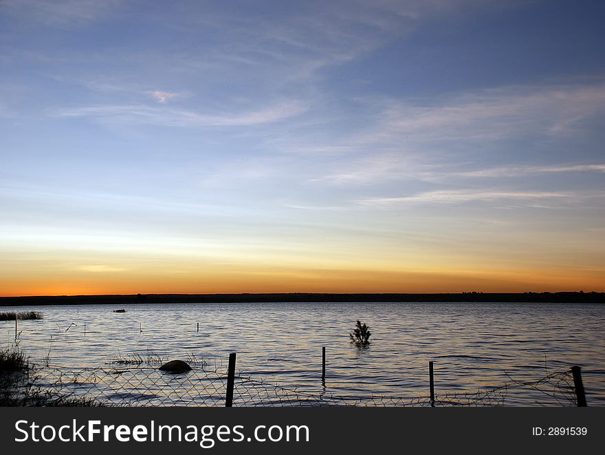 Lake sunset with a submerged chainlink fence in the foreground. Lake sunset with a submerged chainlink fence in the foreground