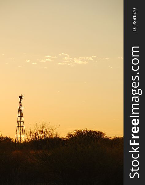 Sunset in the Kalahari desert in South Africa. Silhouette of a windpump in the foreground. Sunset in the Kalahari desert in South Africa. Silhouette of a windpump in the foreground.