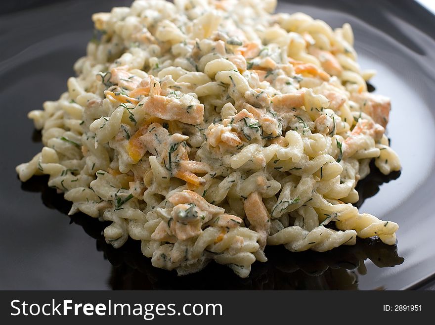 Colorful pasta with green on a black plate