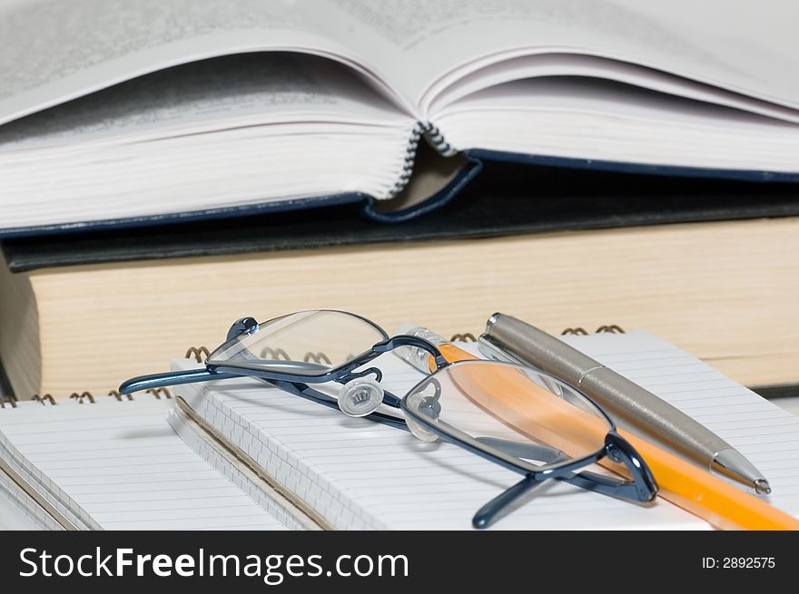 Eyeglasses, pen and pencil on a open notepad. Eyeglasses, pen and pencil on a open notepad