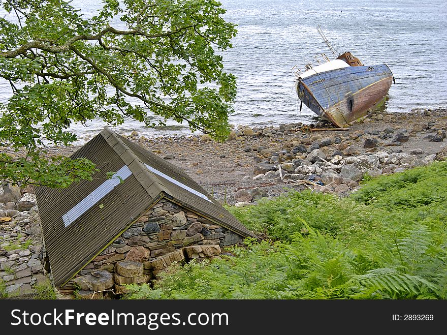An abandoned beached fishing boat on the shore of Loch Torridon at Diabaig, North West Scotland. A small stone built hut fills the foreground. An abandoned beached fishing boat on the shore of Loch Torridon at Diabaig, North West Scotland. A small stone built hut fills the foreground