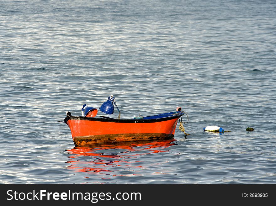 Small red painted fishing boat lies at anchor. Small red painted fishing boat lies at anchor