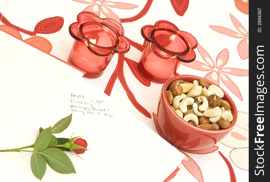 Book, rose, candles and a bowl of mixed nuts. The book have an inscription with birthday wishes. Book, rose, candles and a bowl of mixed nuts. The book have an inscription with birthday wishes