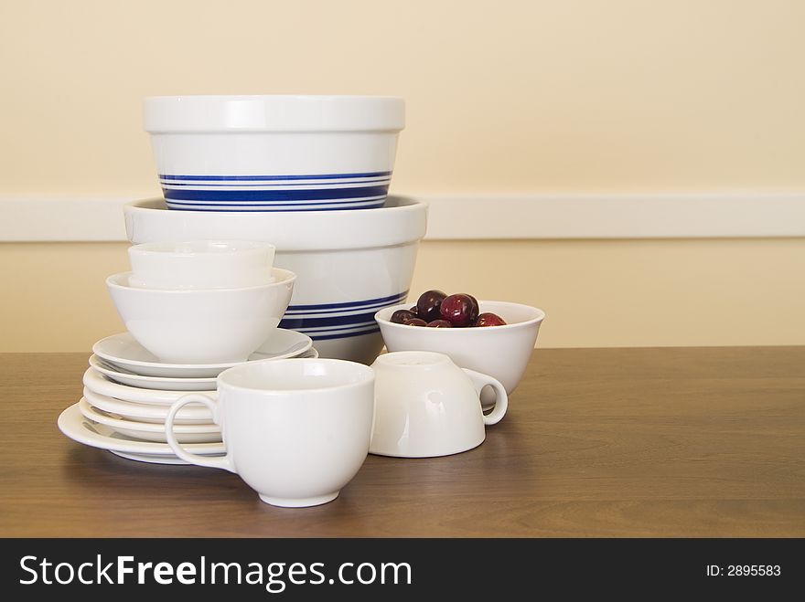 Group of dishes, cups, and bowls on dark wood table in a horizontal format. Group of dishes, cups, and bowls on dark wood table in a horizontal format.