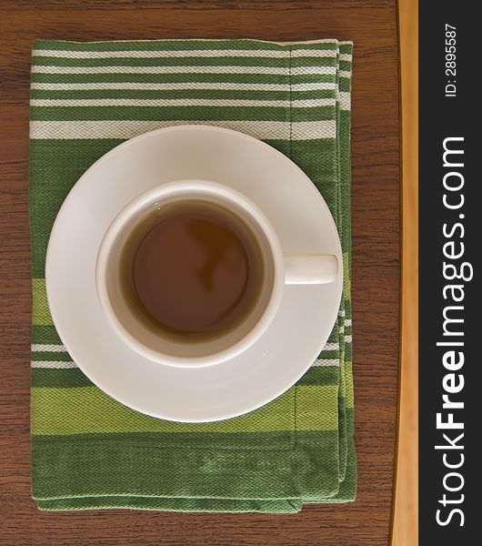 Tea cup seen from above on a coffee table and green nakpkin. Tea cup seen from above on a coffee table and green nakpkin.