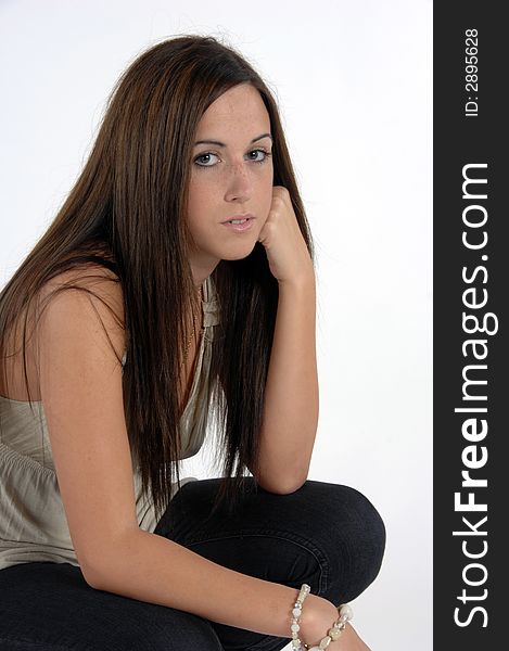 Young women crouching down resting face on hands against a white background. Young women crouching down resting face on hands against a white background