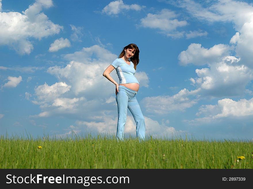 Smiling pregnant woman on cloudy sky background. Smiling pregnant woman on cloudy sky background