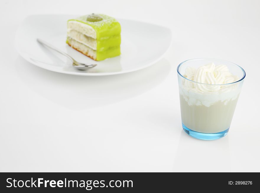 Glass of Frappucino with creamy top and piece of green cake. Glass of Frappucino with creamy top and piece of green cake.