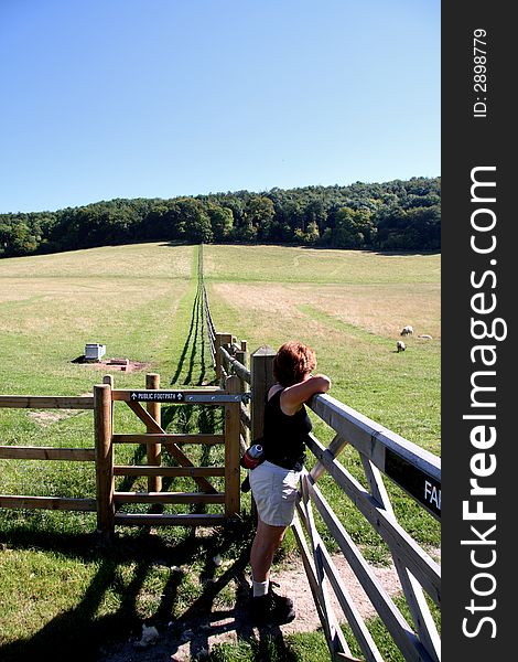 Lady Hiker on Rural English Footpath leaning on a gate and admiring the Scenery