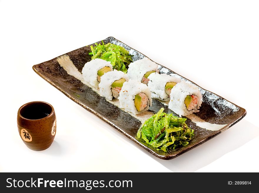 A plate of california rolls and sake cup on white background