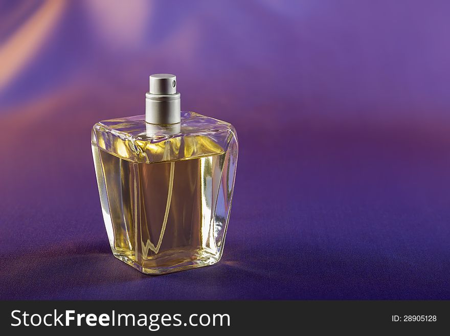 Perfume in a glass bottle against a purple backgroun. Perfume in a glass bottle against a purple backgroun.