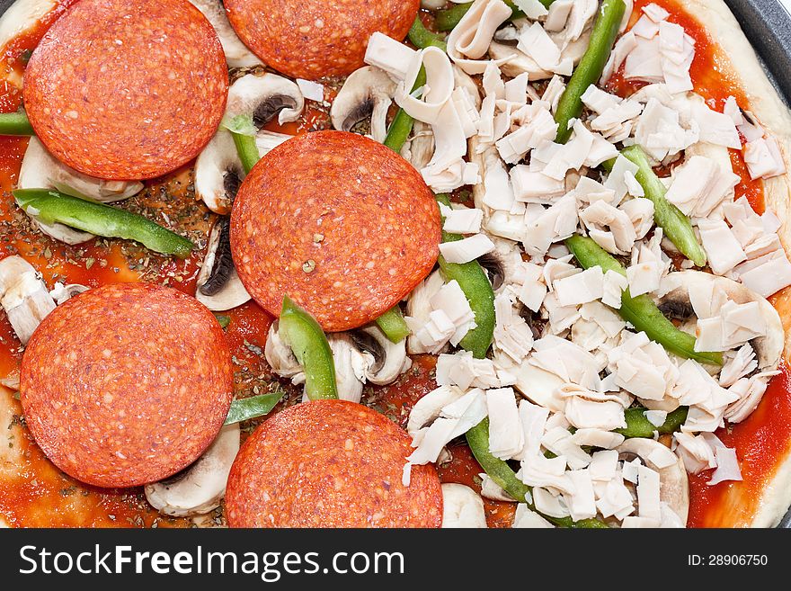 Pizza dough with tomato sauce, oregano, mushrooms, green peper, pepperoni and ham. Pizza dough with tomato sauce, oregano, mushrooms, green peper, pepperoni and ham