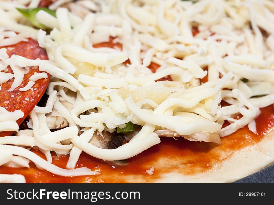 Pizza dough with tomato sauce, oregano, mushrooms, green pepper, pepperoni, ham and shredded mozzarella cheese. Pizza dough with tomato sauce, oregano, mushrooms, green pepper, pepperoni, ham and shredded mozzarella cheese