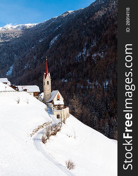 A wintertime view of a small church with a tall steeple in the Sud Tyrol, Italy.