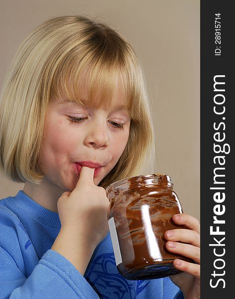 Little girl eating chocolate cream.Kid eating nut chocolate cream. Little girl eating chocolate cream.Kid eating nut chocolate cream.