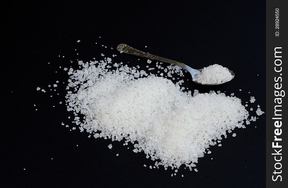 Salt on a black background with small spoon. Salt on a black background with small spoon