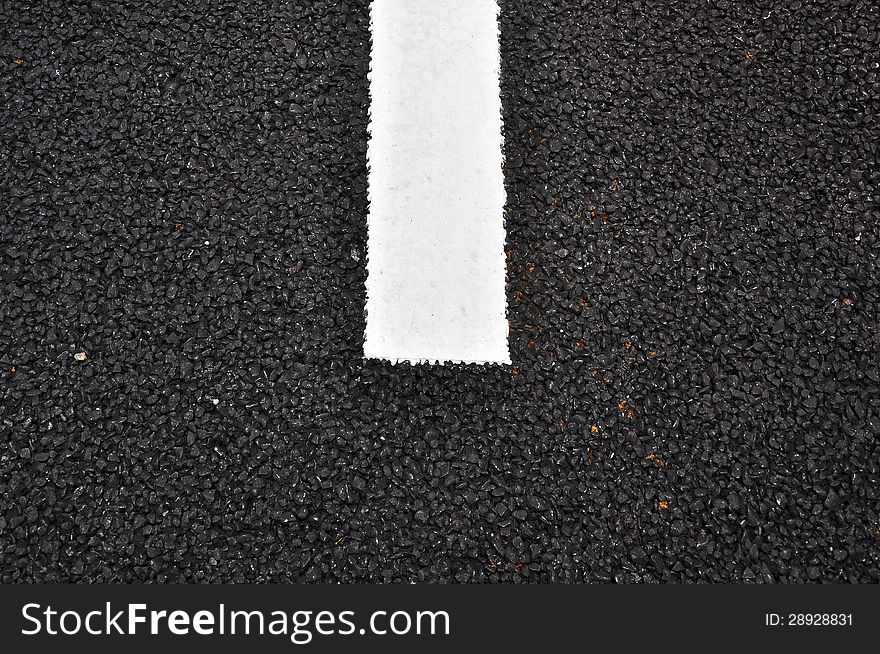 Closeup of a tar or asphalt pavement texture with a white line painted