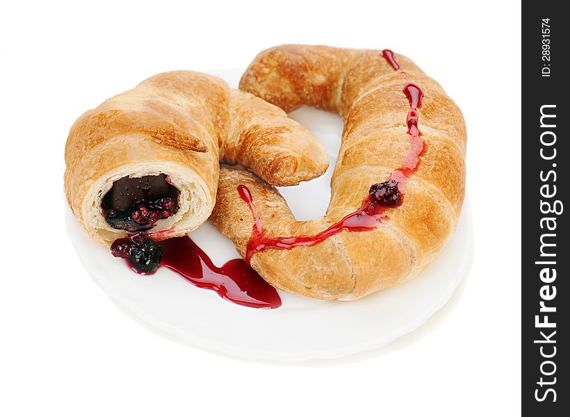 Fresh and tasty croissant with chocolate and raspberry jam on plate isolated on white background
