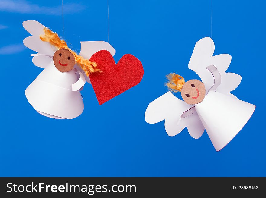 Two toy angel and a heart on a blue background. Two toy angel and a heart on a blue background