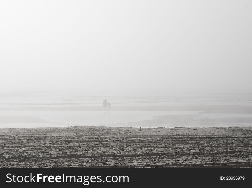 Two people walking on the beach in the fog. Two people walking on the beach in the fog.
