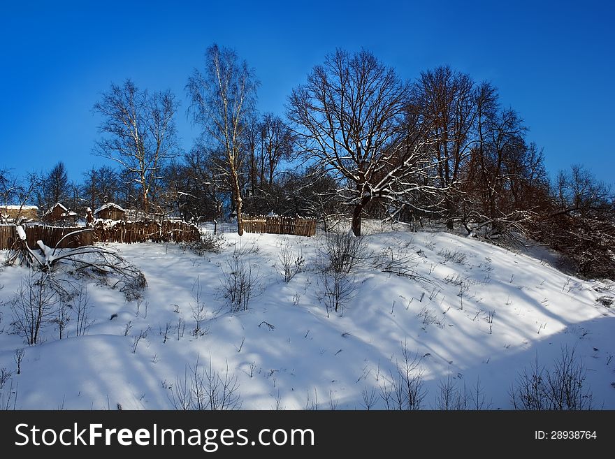 Winter landscape with old sheds, wooden fences and trees on the hill. Winter landscape with old sheds, wooden fences and trees on the hill