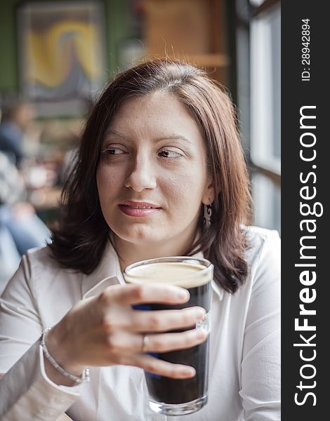 Portrait of a young woman drinking a pint of stout beer. Portrait of a young woman drinking a pint of stout beer.