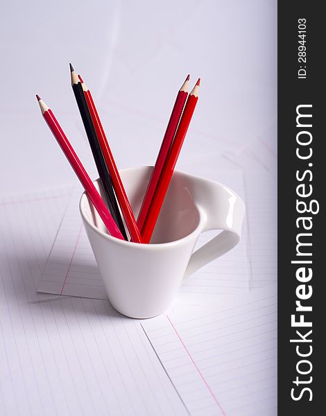 Black and red pencils stand in a white cup