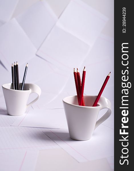 Black and red pencils stand in two white cups