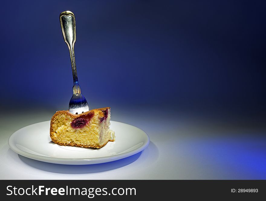 Fork in cake on white plate, gradient from blue to white in the background.