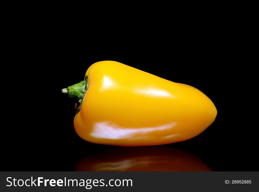 A yellow peppers on black background with reflection