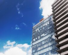Bottom View Of Modern Office Building On Background Of Blue Sky With White Clouds. Royalty Free Stock Photos