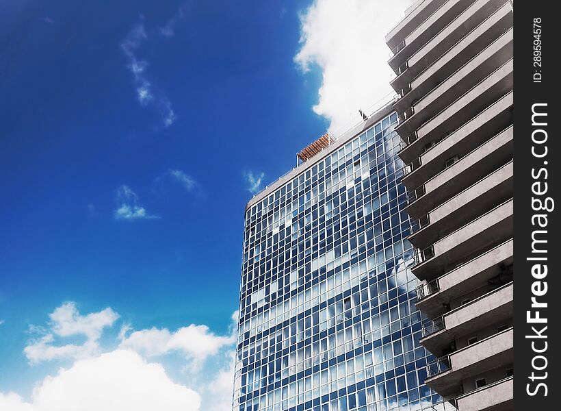Bottom view of modern office building on background of blue sky with white clouds.