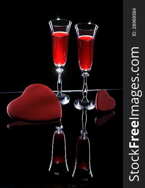 Two wine glasses and hearts on a dark background