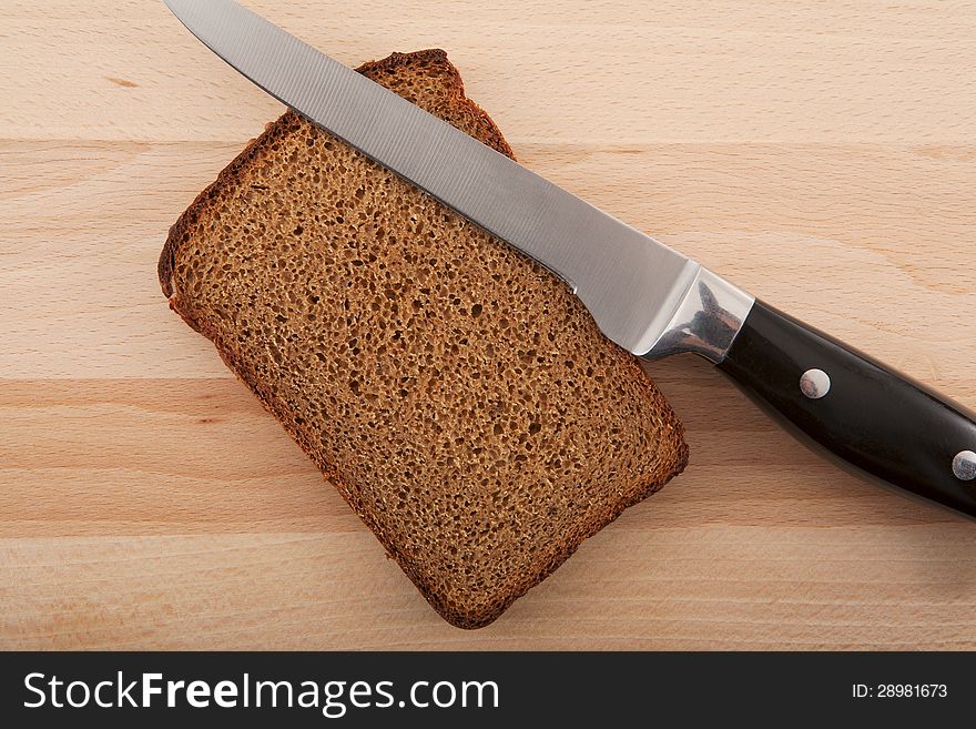 Knife and chopped rye bread on cutting board wooden