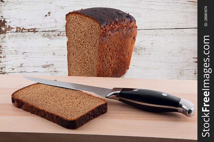 Knife and chopped rye bread on cutting board wooden
