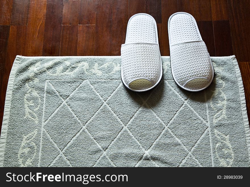 WHITE SLIPPERS AND MAT ON WOOD FLOOR. WHITE SLIPPERS AND MAT ON WOOD FLOOR