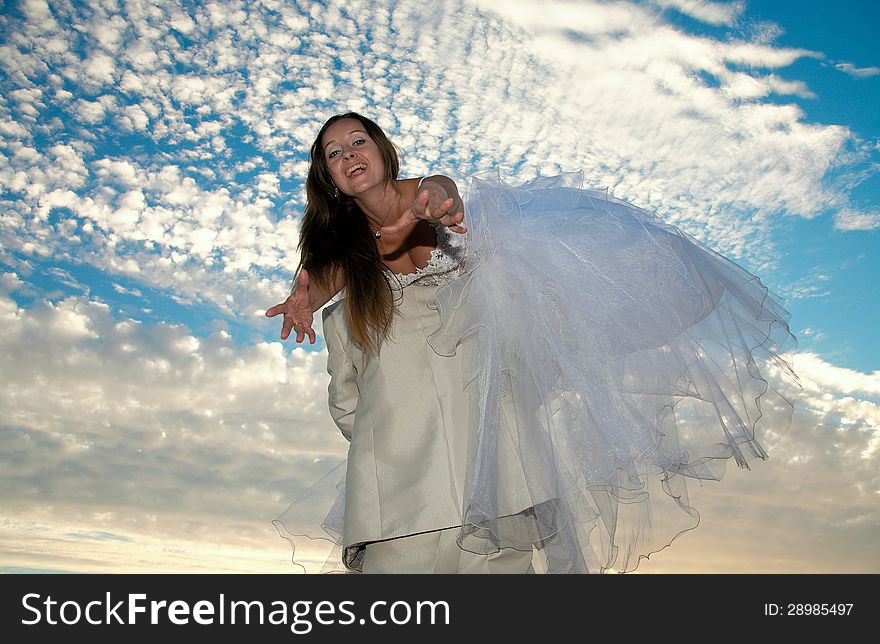Bride in a wedding dress on a background of the blue sky. Bride in a wedding dress on a background of the blue sky.