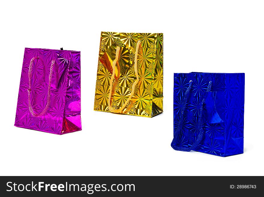 Three isolated holographic paper gift bags of magenta, gold and blue. Three isolated holographic paper gift bags of magenta, gold and blue.